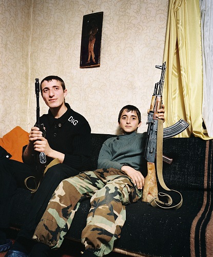 Rob Hornstra, Brothers Zashrikwa (17) and Edrese (14) pose proudly with a kalashnikov on the sofa in their aunt and uncles house, Kuabchara, Abkhazia, 2009.  Rob Hornstra/Flatland Gallery