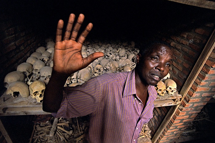 Nyamata, Ruanda, 2003. Epimaque Rwema (50), sopravvissuto al genocidio. Nyamata, 25 km a sud di Kigali,  uno dei luoghi simbolo del genocidio perpetrato dagli Hutu nella primavera del 1994. Nella chiesa di Nyamata furono massacrate diecimila civili inermi di etnia Tutzi. Nella foto Epimaque Rwema (50 anni), sopravvissuto al genocidio, ha perso tutti i famigliari. Sullo sfondo i teschi di alcune vittime raccolti nei sotterranei della chiesa.  Livio Senigalliesi.