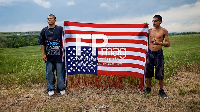 From the exhibition Mitakuye Oyasin by Aaron Huey, exposed at Festival della Fotografia Etica 2016, Lodi, October, 8th - 30th 2016.
Oglala youths hold an upside-down flag, an international symbol of distress and an act of defiance toward the U.S. government, at a rally to commemorate a 1975 shoot-out between American Indian Movement (AIM) activists and FBI agents. Two agents and one AIM member died; AIMs Leonard Peltier was jailed for life. Foto  Aaron Huey.