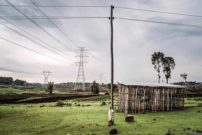 Fausto Podavini, A circa 40 Km da Addis Abeba in direzione di Butajira, la nuova linea elettrica si incrocia con la vecchia linea. Etiopia del sud, 2016. Solamente parte della produzione di energia elettrica verrà utilizzata per il paese. La restante energia prodotta, è già stata venduta dal Governo Etiope alle Nazioni confinanti come Kenya e Gibuti. Un accordo contrattuale di 35 milioni di euro è stato firmato tra l'Etiopia Electric Power Corporation (EEPCo) e la società cinese limitata TBEA per l'installazione di linee di trasmissione di energia da Gibe III alla sottostazione di Wolayta Sodo. Di questi, l'85 per cento deve essere coperto dalla EXIM Bank del governo cinese. Nonostante l’enorme quantità di energia prodotta, attualmente gran parte dei villaggi del sud della valle dell’Omo non hanno corrente elettrica diretta. © Fausto Podavini.