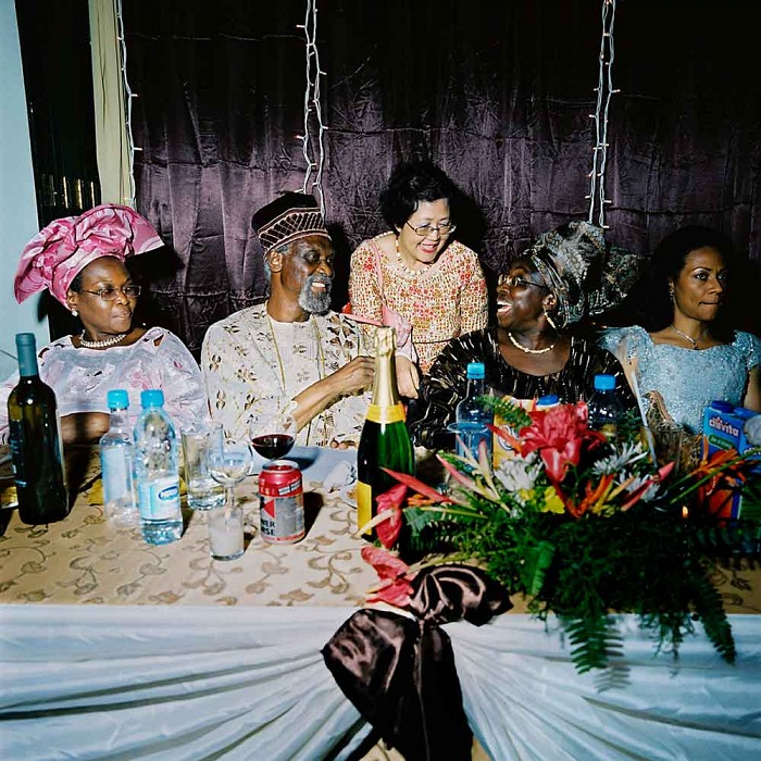 Nigeria, Lagos, 2007. Mrs. Wood in her immense restaurant, the 5 floors, 1500 seats Golden Gates of Lagos. The senator, Anthony Mogbongubola Soetan (on the left of the Champagne bottle) has come here to celebrate his 70th birthday in the company of about 300 guests, all members of the Nigerian elite. © Paolo Woods/Anzenberger, dalla serie Chinafrica