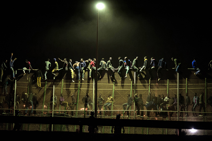 Giulio Piscitelli, Immigrati subsahariani cercano di scavalcare la rete di confine tra Spagna e Marocco, Melilla, Spagna, agosto 2014. © Giulio Piscitelli/Contrasto