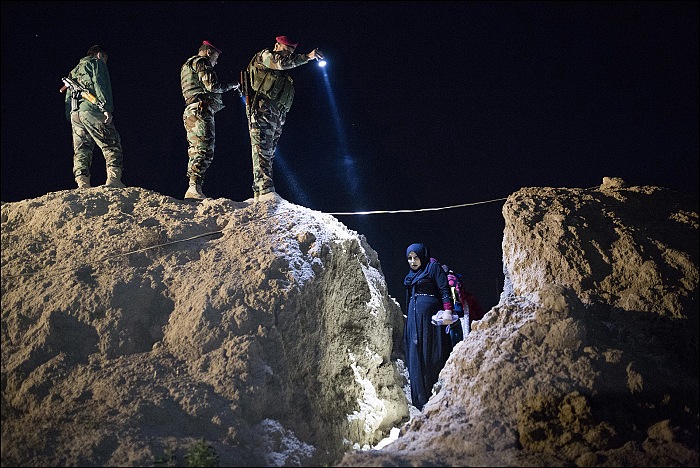 Attraverso una delle poche brecce nella linea difensiva, una donna incinta attraversa la linea del fronte, 19 aprile 2016. Siamo a Doogrdkan, a 56km a sud di Mossoul.  Frdric Lafargue per Paris Match.