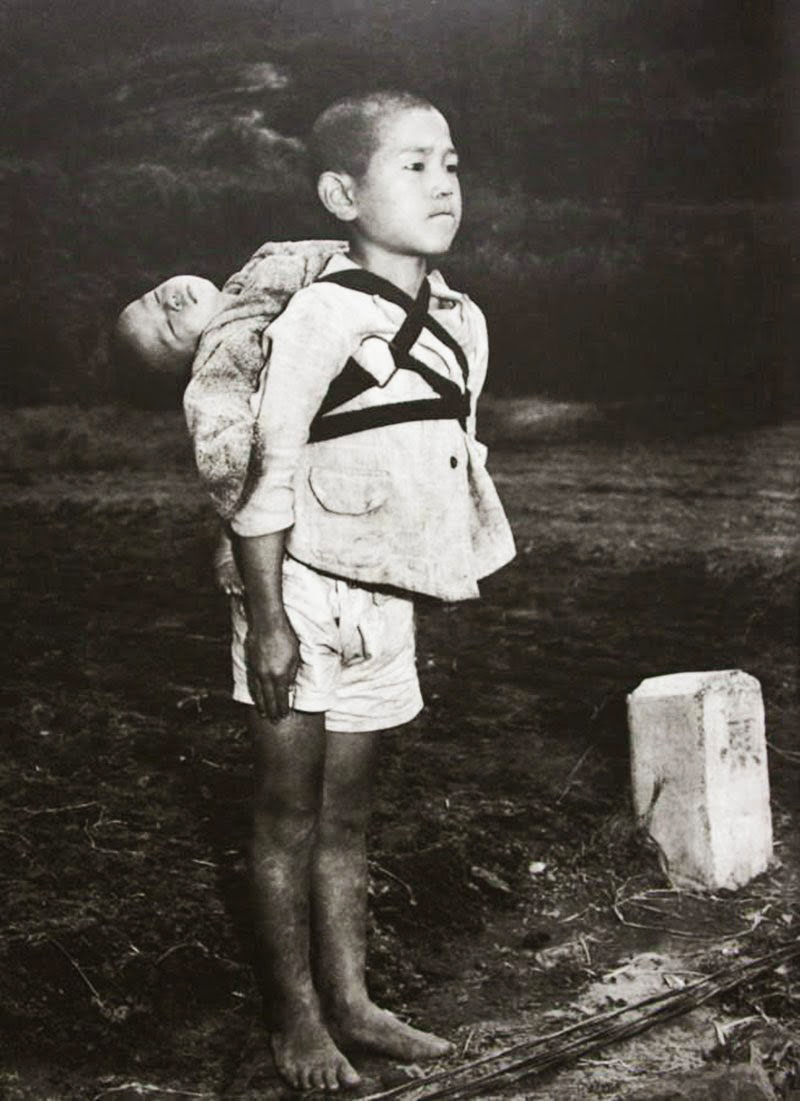 Joseph Roger O'Donnell, Un ragazzo giapponese in piedi sull'attenti dopo aver portato il fratello minore morto a una pira per la cremazione. © Joseph Roger O'Donnell.